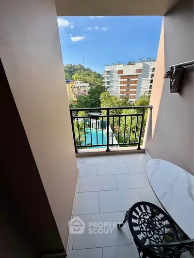 Charming balcony with a stunning view of lush greenery and modern buildings, perfect for relaxation.