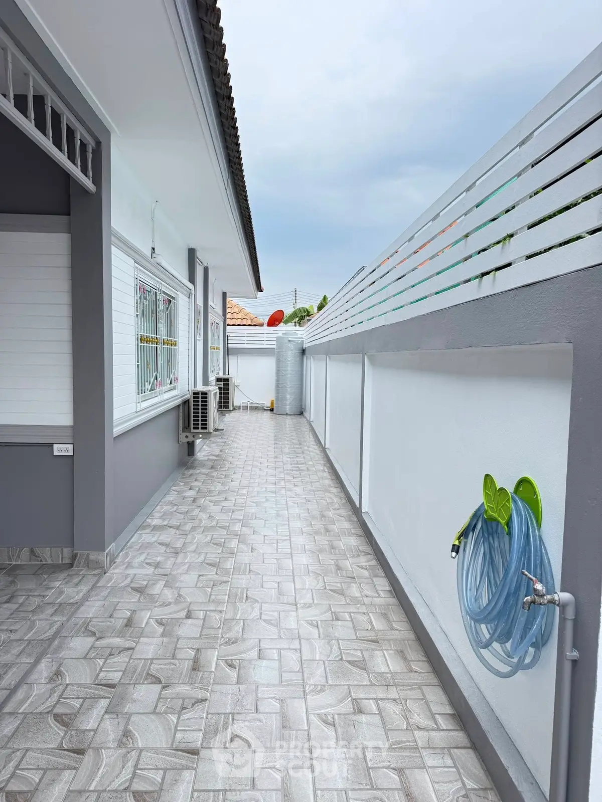 Modern exterior with sleek tiled walkway and hose reel, perfect for easy maintenance and outdoor activities.