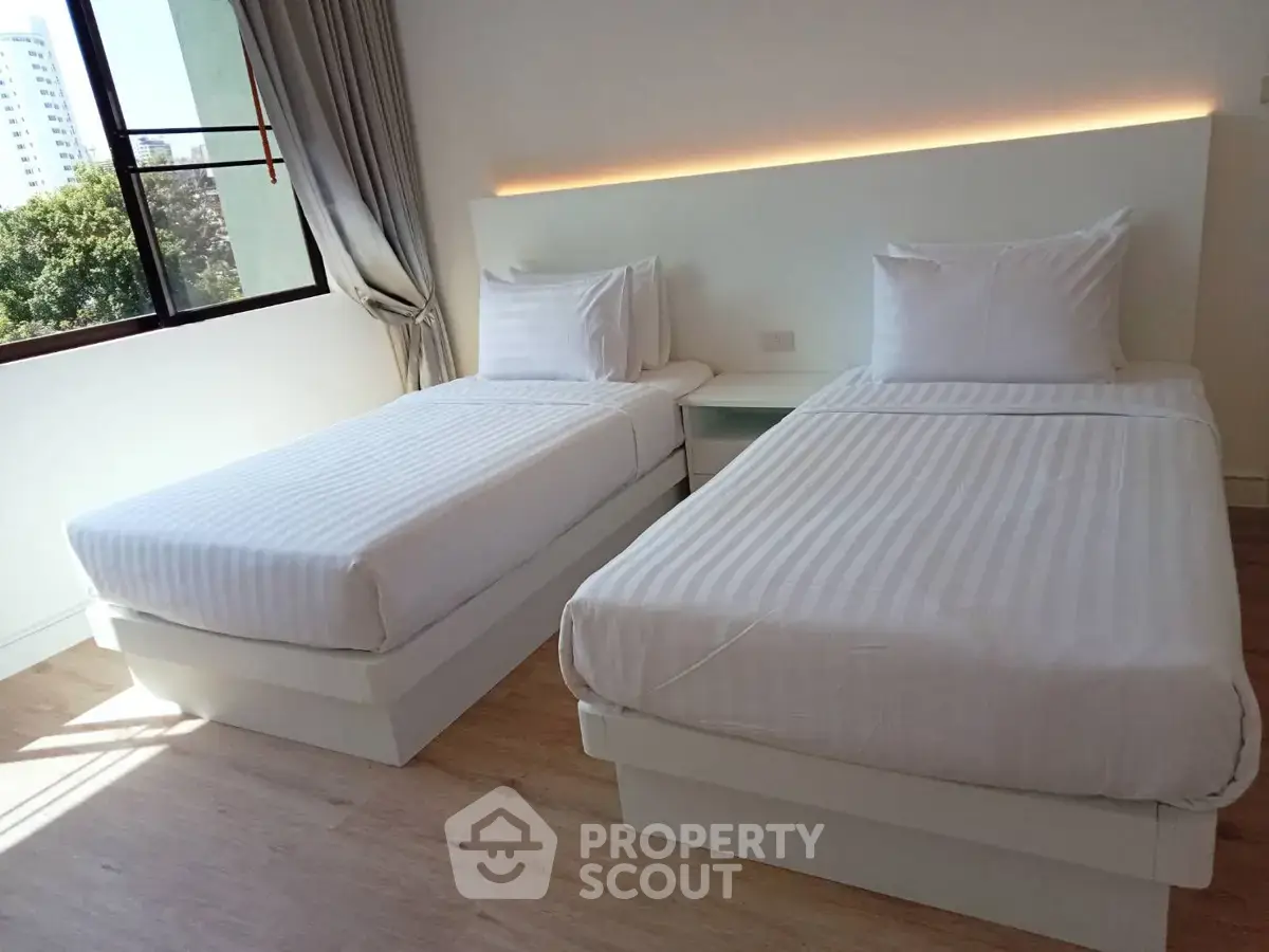Modern bedroom with twin beds and large window offering city view