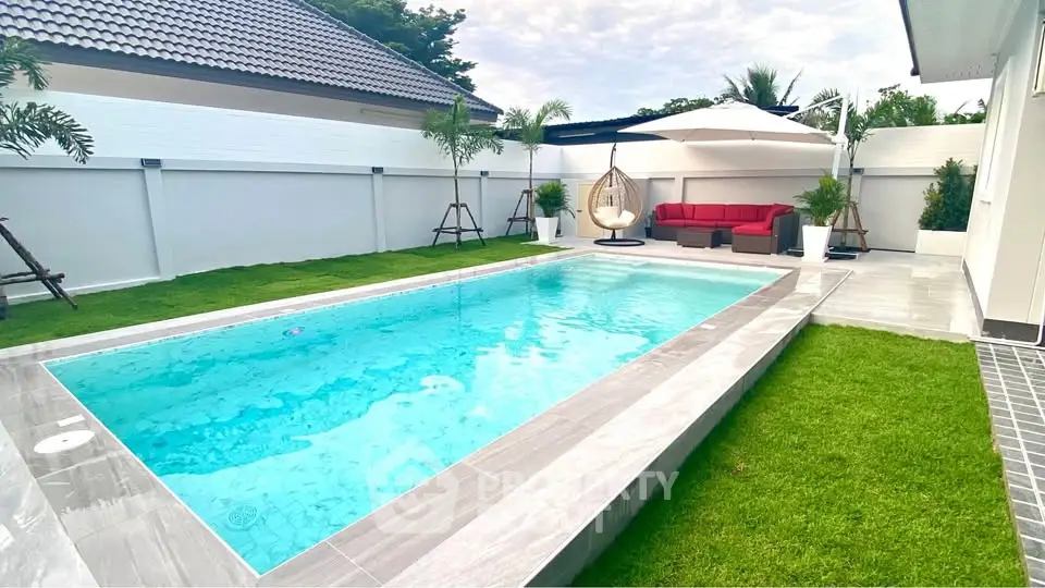 Luxurious backyard with a pristine pool, lush green lawn, and stylish outdoor seating area.