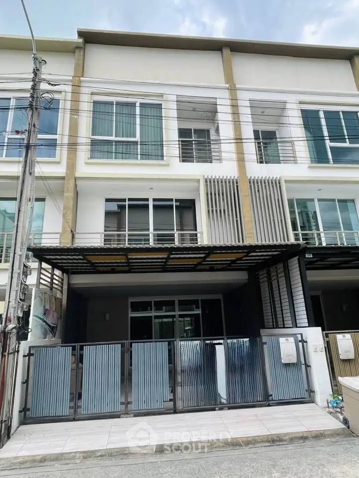 Modern townhouse exterior with gated entrance and large windows in a residential area.