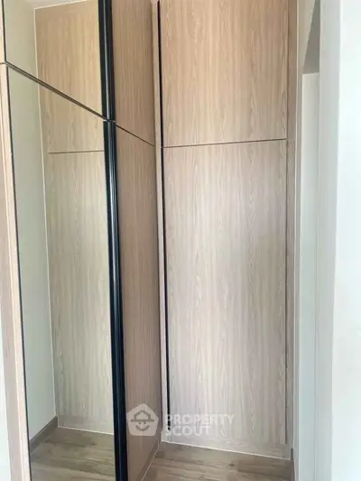 Modern wooden wardrobe with mirrored sliding doors in a stylish interior space.