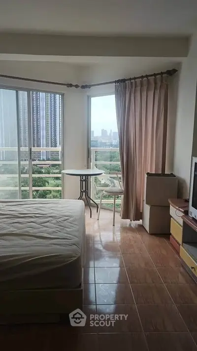 Cozy bedroom with balcony offering stunning city view, perfect for urban living.