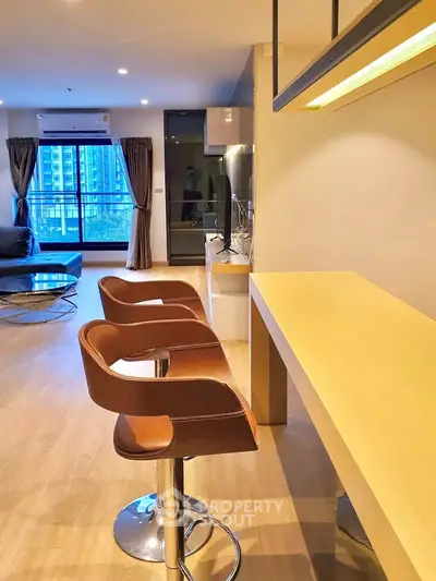 Modern living room with stylish bar stools and large windows offering city views.