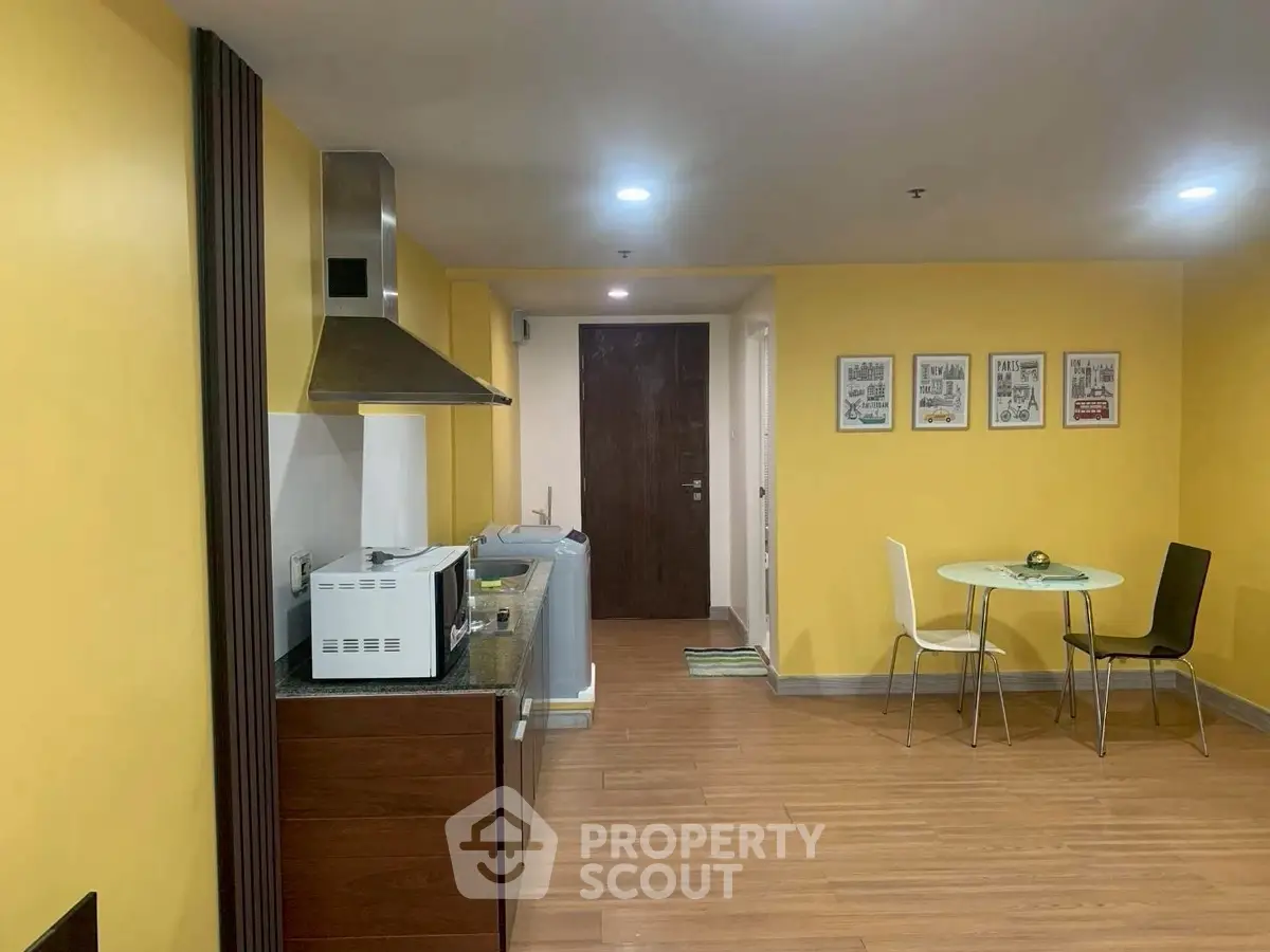 Modern kitchen with yellow walls, dining area, and appliances in a cozy apartment.