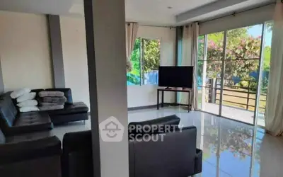 Spacious living room with modern furniture and large windows overlooking a garden.