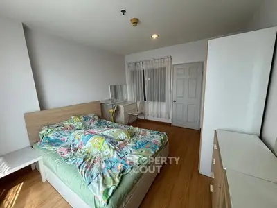 Cozy bedroom with colorful bedding and wooden furniture, perfect for relaxation.