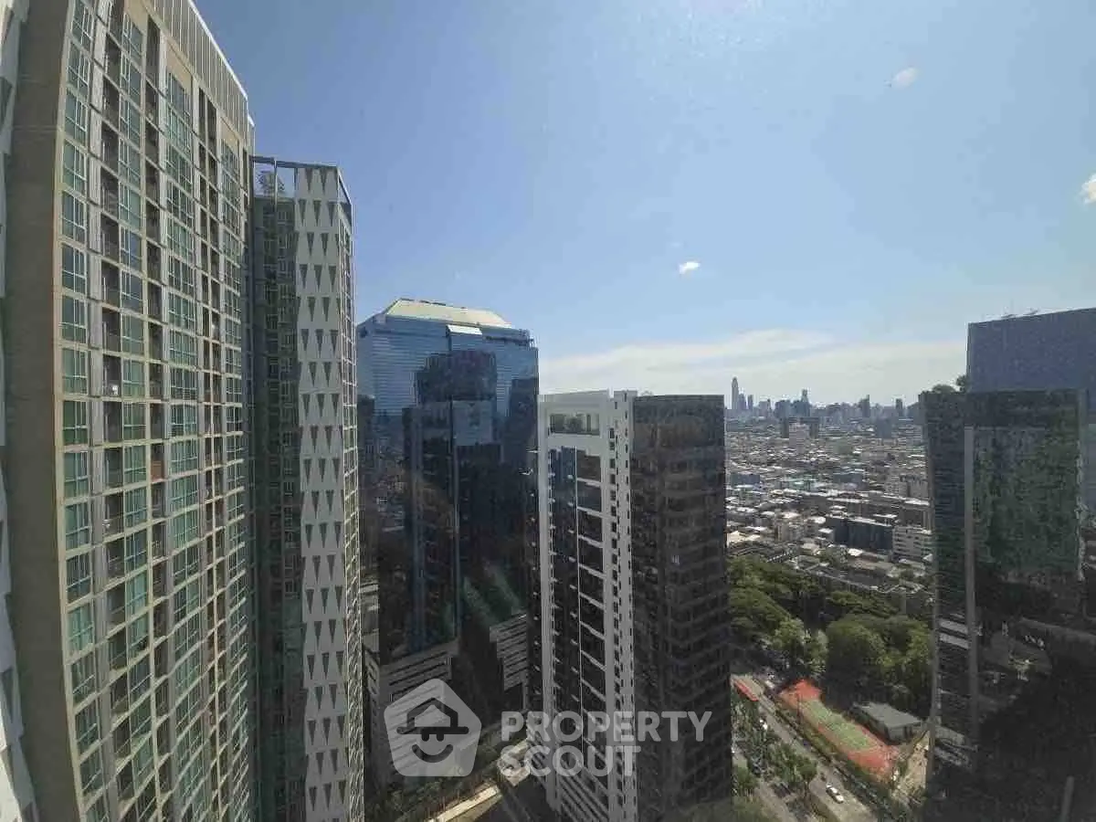 Stunning cityscape view from high-rise building with modern architecture and clear blue sky.