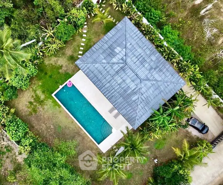 Stunning aerial view of modern villa with private pool surrounded by lush greenery, perfect for luxury living.