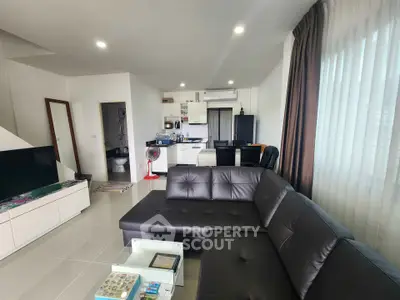 Modern living room with sleek black leather sofa and open kitchen layout
