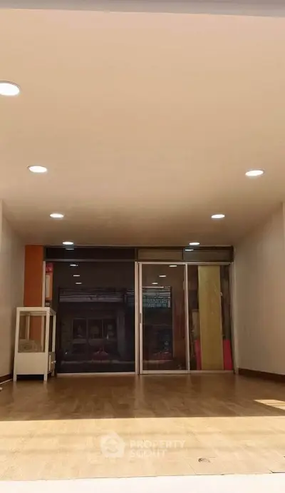 Spacious modern living room with wooden flooring and large glass doors for natural light.