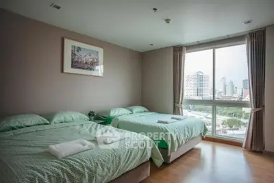 Spacious bedroom with two beds and city view, perfect for urban living.