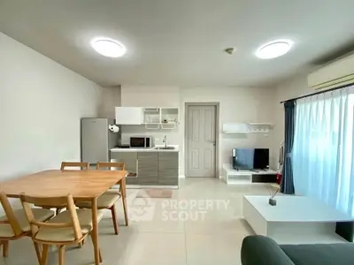 Modern open-plan living room with dining area and compact kitchen in bright apartment.