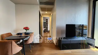 Modern living room with stylish dining area and large TV, featuring elegant decor and natural light.