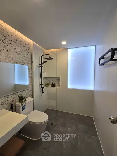 Modern bathroom with sleek fixtures and stylish lighting, featuring a spacious shower area and elegant design.