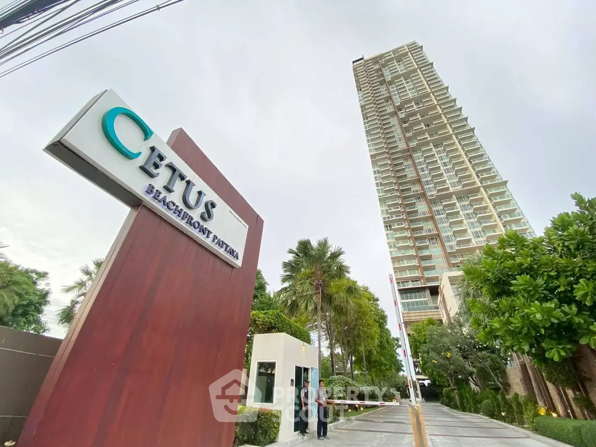 Luxurious beachfront high-rise building with lush greenery and modern entrance signage.