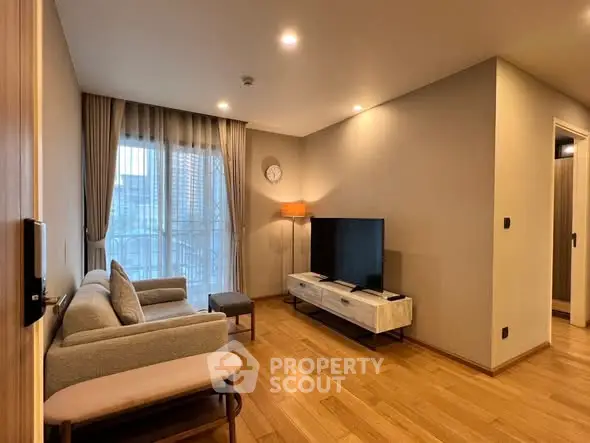 Modern living room with wooden flooring, stylish furniture, and a large TV, perfect for relaxation.