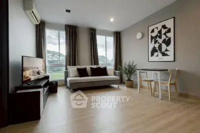 Modern living room with stylish decor, large windows, and wooden flooring.