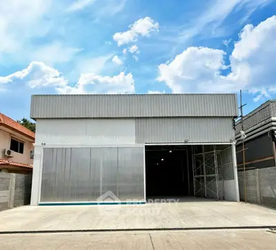 Spacious industrial warehouse with large entrance and clear blue sky