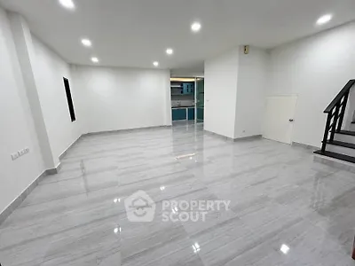 Spacious modern living room with sleek flooring and staircase, ideal for contemporary living.