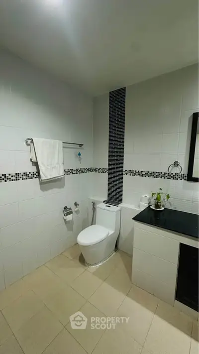 Modern bathroom with sleek black and white tile design and contemporary fixtures.