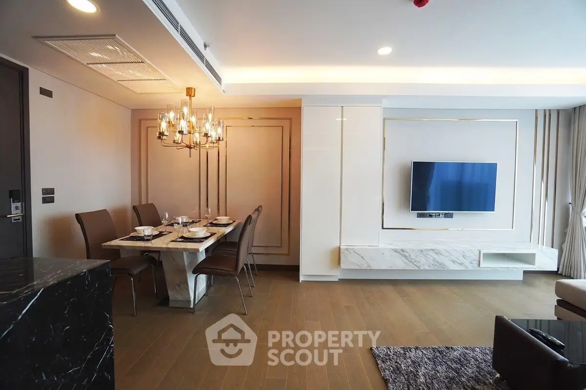 Luxurious modern living room with elegant dining area and wall-mounted TV, featuring chic lighting and stylish decor.