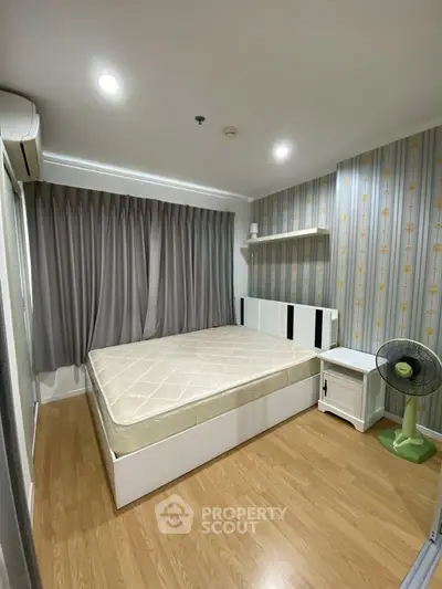 Cozy bedroom with modern decor, featuring a comfortable bed, stylish wallpaper, and wooden flooring.