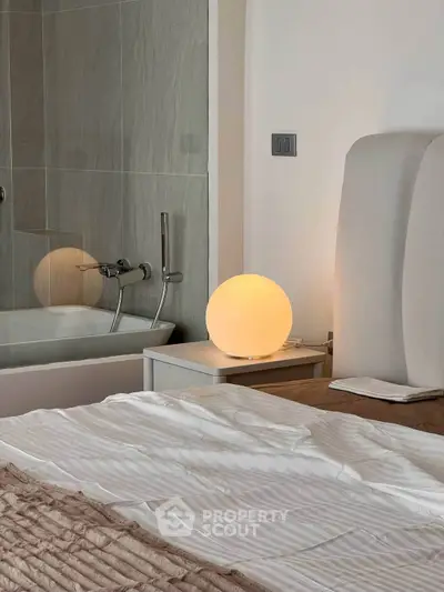 Modern bedroom with stylish lighting and partial view of a sleek bathroom