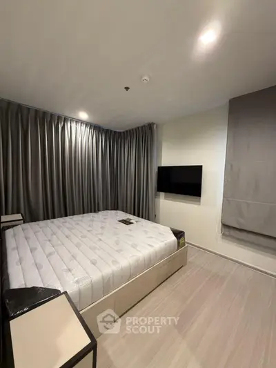 Modern bedroom with sleek design, featuring a large bed and wall-mounted TV, perfect for relaxation.