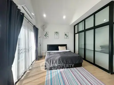 Spacious bedroom with modern decor, large windows, and stylish frosted glass wardrobe.