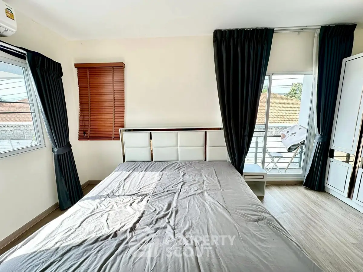 Spacious bedroom with large windows and balcony access, featuring modern design and ample natural light.
