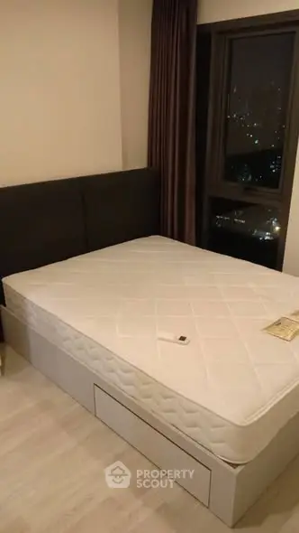 Cozy bedroom with city view, featuring a comfortable bed and modern decor.