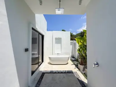 Luxurious outdoor bathroom with modern bathtub and tropical plants, perfect for a serene retreat.