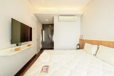Modern bedroom with wall-mounted TV and air conditioning, featuring a minimalist design and cozy ambiance.