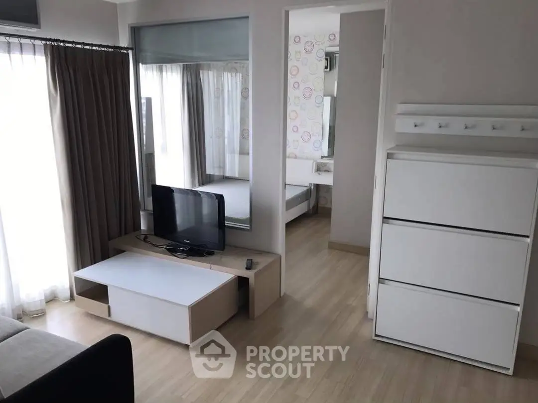 Modern living room with sleek furniture and natural light, featuring a TV and stylish decor.