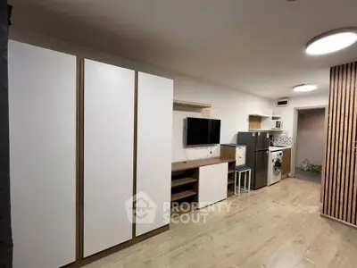 Modern living room with sleek storage and appliances, featuring a washing machine and fridge.