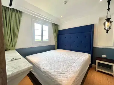 Elegant bedroom with plush blue headboard and natural light from window
