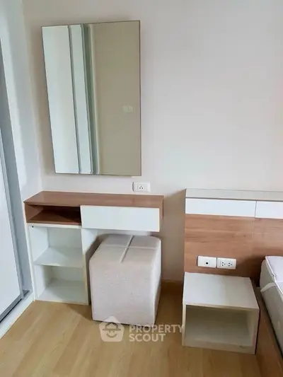 Modern bedroom with stylish vanity and mirror, featuring sleek wooden accents and neutral tones.