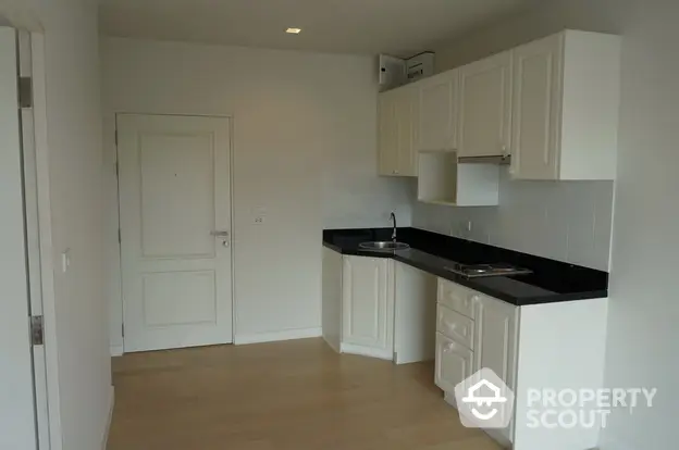 Modern compact kitchen with sleek white cabinets and black countertops