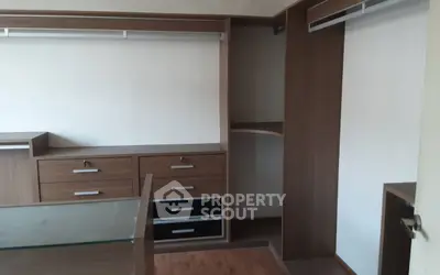 Spacious walk-in closet with modern wooden cabinetry and ample storage space.
