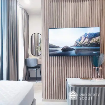 Modern bedroom with stylish decor, featuring a wall-mounted TV and elegant furnishings.