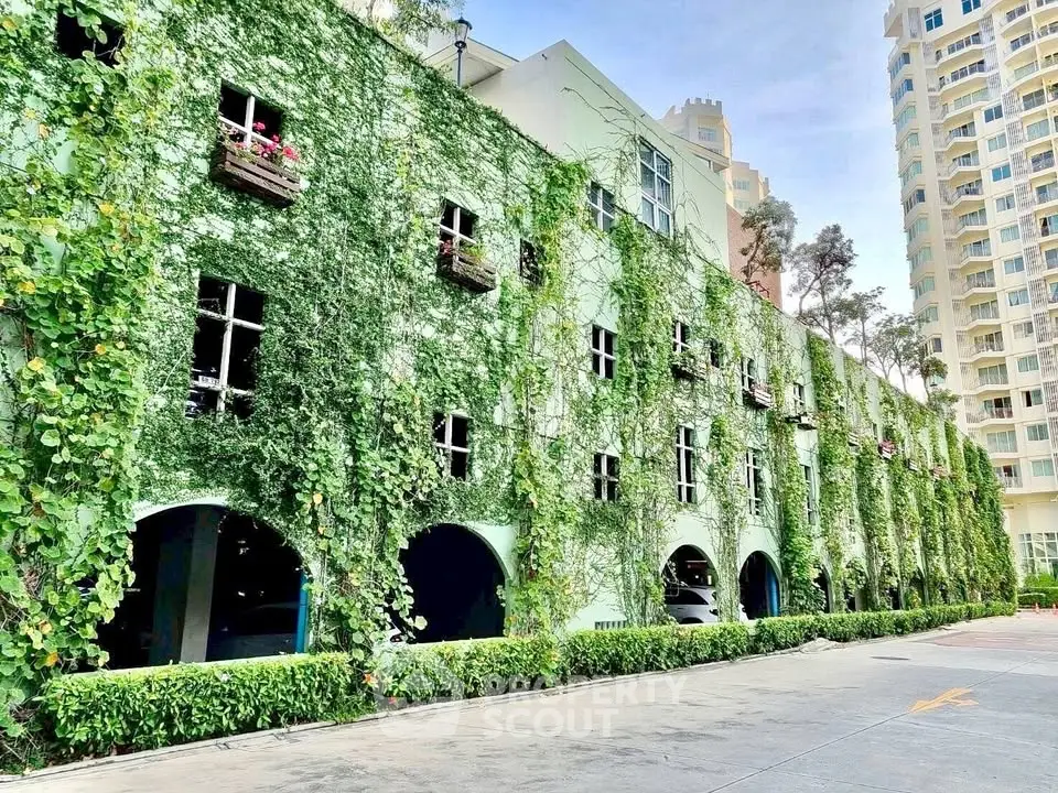 Stunning green facade of a modern building with lush ivy and elegant windows, perfect for eco-friendly living.