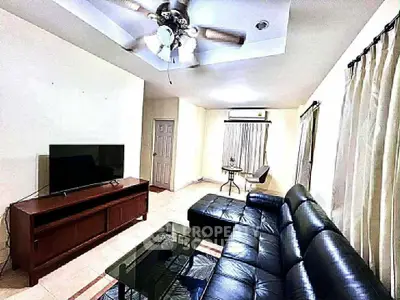 Spacious living room with modern leather sofa and ceiling fan, perfect for relaxation.