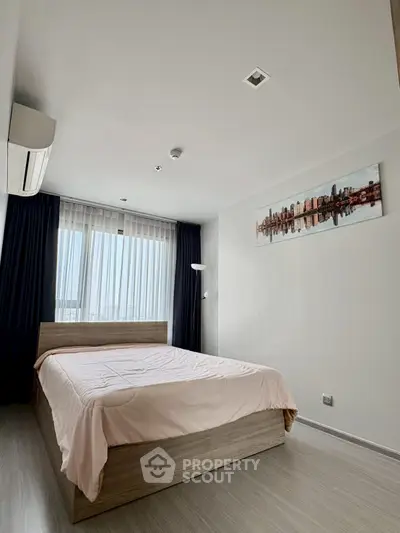 Modern bedroom with large window and stylish decor in a contemporary apartment.