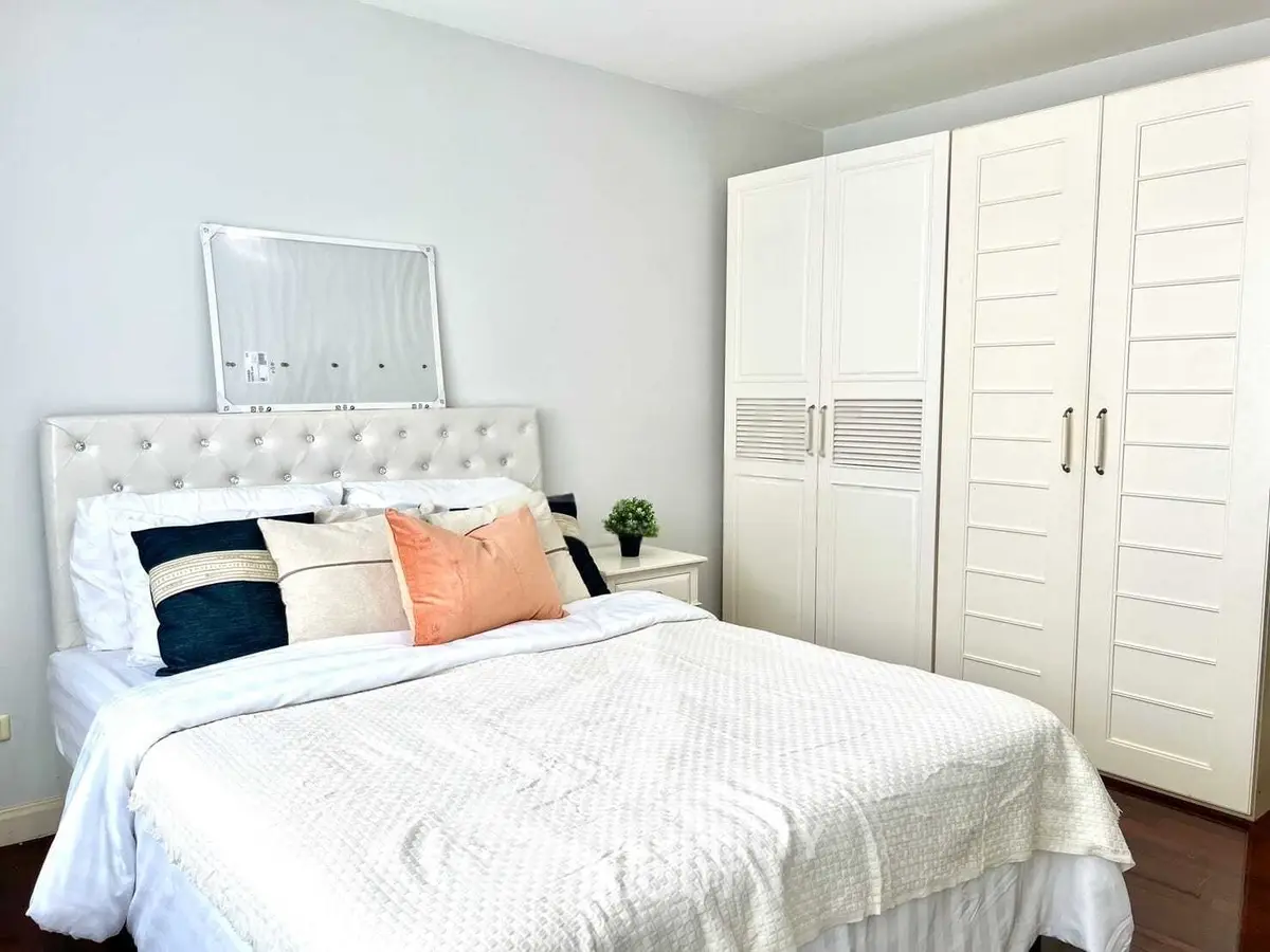 Elegant bedroom with plush bed and spacious wardrobe in modern apartment.