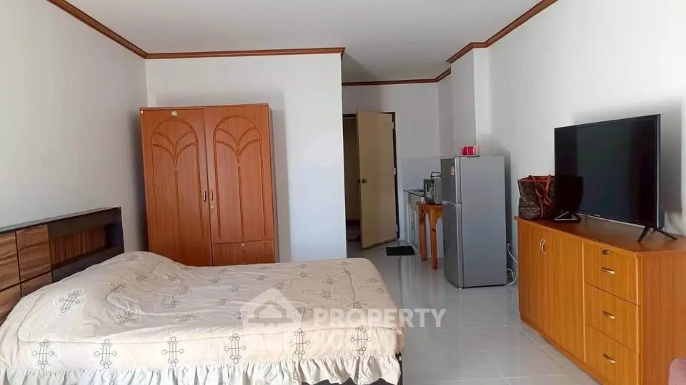 Spacious bedroom with modern furnishings and kitchenette in a cozy apartment.