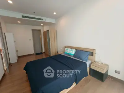 Spacious modern bedroom with wooden flooring and stylish decor in a luxury apartment.