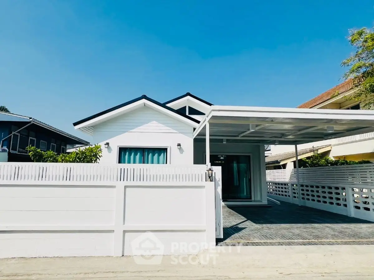 Charming white bungalow with modern design and spacious carport in a serene neighborhood.