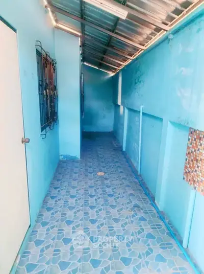 Charming blue-tiled corridor with metal roof and secure door, perfect for cozy outdoor living.