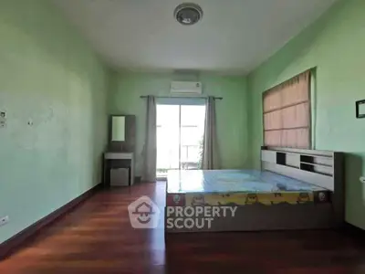 Spacious bedroom with wooden flooring and natural light